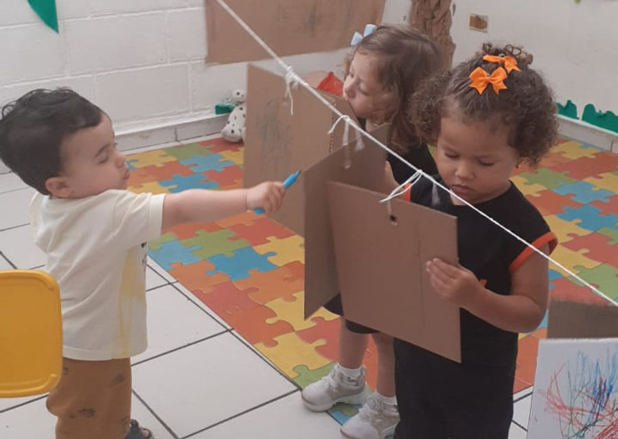 Crianças pequenas brincando e pintando no berçário